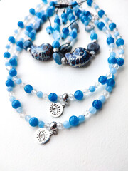 Blue stone aquamarine apatite kyanite beaded jewelry flat lay close up. Choker necklaces with eye charms, bracelets. Natural semiprecious stone jewelry, accessories, fashion collection, crafts, jewel