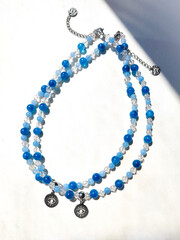 Pair of blue stone aquamarine apatite beaded chokers with eye charms flat lay top view close up. Natural semiprecious stone jewelry, accessories, fashion collection, crafts, jewellery