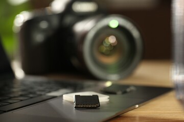 SD memory cards, holder, laptop and photo camera on wooden table, closeup