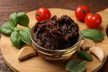 Delicious sun dried tomatoes, fresh vegetables, basil and garlic on wooden table, closeup