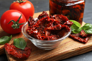 Tasty sun dried tomatoes and fresh vegetables on black table, closeup
