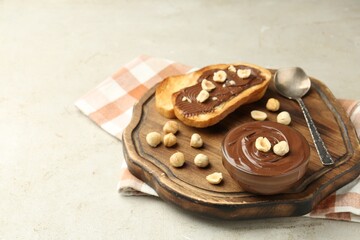Toasts with tasty chocolate spread and hazelnuts on light table, closeup. Space for text