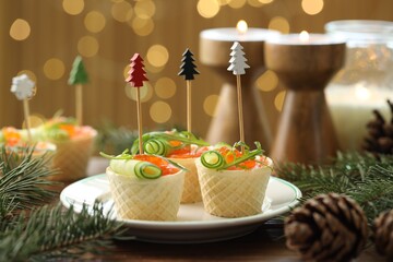 Tasty canapes and festive decor on wooden table against blurred lights, closeup. Bokeh effect