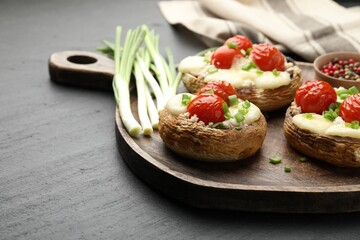 Tasty stuffed mushrooms served on black table, closeup