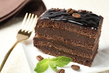 Piece of chocolate cake served with mint and fork on white table, closeup