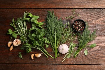 Different fresh herbs and spices on wooden table, flat lay