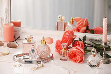 Bottles of different perfumes, accessories and flowers on dressing table indoors