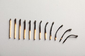 Burnt matches on grey background, flat lay