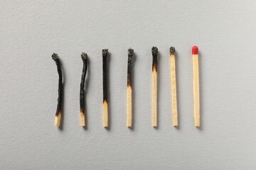 Burnt and whole matches on grey background, flat lay