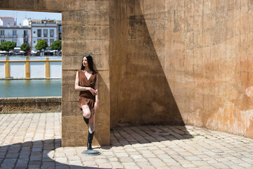 Latin woman, young and pretty brunette with tattoos on her arms and legs, wearing a brown dress and...