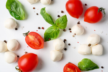 Tasty mozzarella balls, tomatoes, peppercorns and basil on white background, flat lay