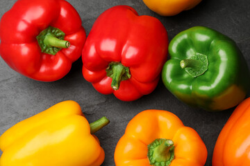 Fresh colorful bell peppers on dark gray table, flat lay