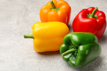 Fresh colorful bell peppers on gray textured table, closeup