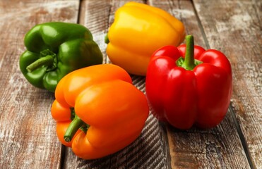 Fresh colorful bell peppers on wooden table, closeup