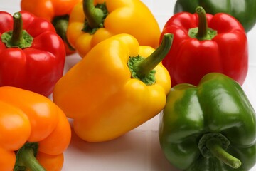 Fresh colorful bell peppers on light table, closeup