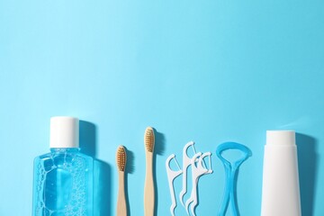 Different oral care products on light blue background, flat lay. Space for text
