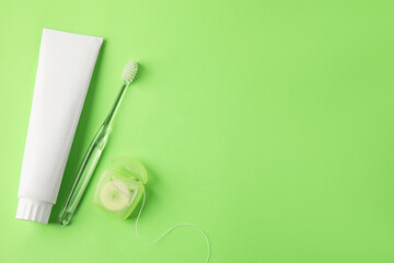 Toothbrush, toothpaste and floss on green background, flat lay. Space for text