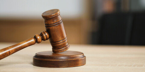 Judge's gavel on wooden table in office, closeup. Space for text