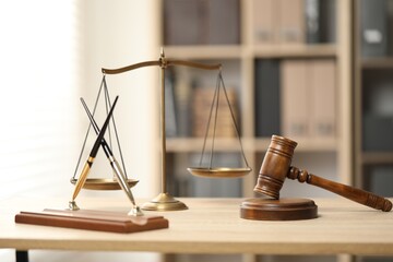 Judge's gavel, scales and fountain pens on wooden table in office