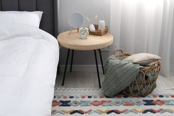 Side table with mirror, alarm clock and decor near bed indoors