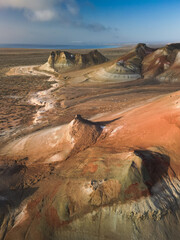 Aerial: across Aktumsik Cape's hills to distant Aral Sea sunrise haze on horizon