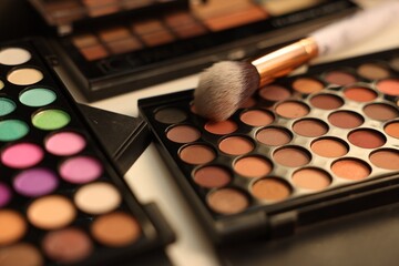 Different makeup products and brush on dressing table, closeup
