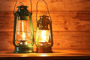 Vintage kerosene lanterns on wooden table, space for text