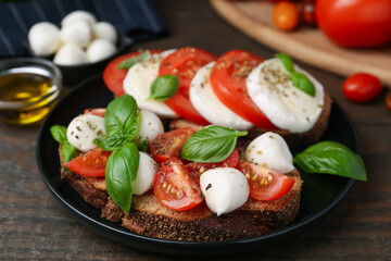 Tasty sandwiches with mozzarella cheese, tomatoes, basil and spices on wooden table, closeup