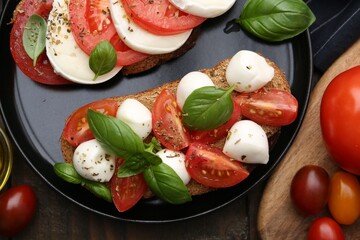 Tasty sandwiches with mozzarella cheese, tomatoes, basil and spices on wooden table, flat lay