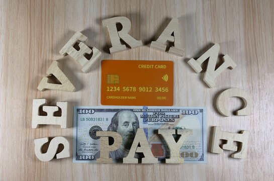 Severance pay sign made of wood and a stack of dollar bills and credit cards.