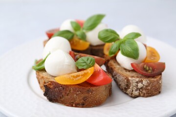 Tasty sandwiches with mozzarella cheese, tomatoes and basil on white table, closeup