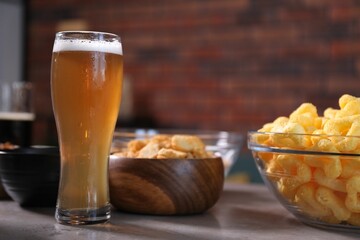 Beer and snacks on grey table indoors, closeup