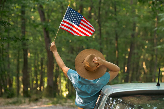 Woman in the car holding a waving american USA flag.