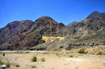 The stony foot of the mountain is strewn with large stones under the scorching sun. Desert hot arid landscape.