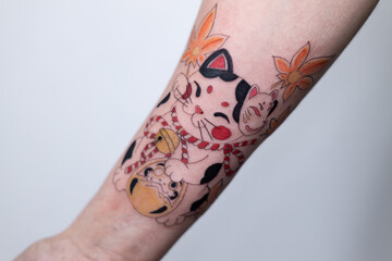 Close-up of a tattoo artist creating a floral tattoo on a woman's hand using a tattoo machine in...