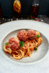 close up of a plate with pasta and meatballs inside