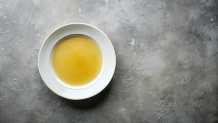 A simple bowl of clear broth on a textured surface
