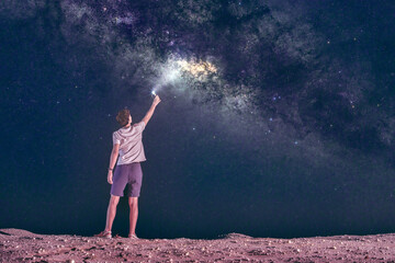 Teen boy shines his smartphone flashlight at the Milky Way Core in Al Qua'a Milky Way spot in Abu Dhabi
