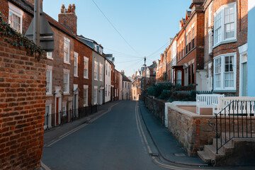 Charming narrow street in a historic town lined with traditional brick buildings and clear blue sky