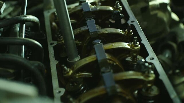 Close-up 8-valve engine block as mechanic tightens cylinder head bolts with torque wrench. Precise valve assembly process shown through careful bolt fastening in automotive repair setting.