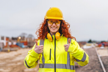 Portrait of femail Construction worker confidently overseeing a building site with equipment and crew members in the background contributing to the project