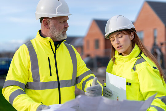 Construction team reviews blueprints in residential development site  for new housing project