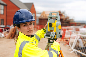 Confident Female Building Surveyor using surveying instrument to conducting measurements at ...