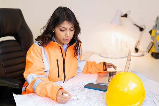 Young female professional architect  working on architectural plans in office