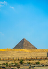 Iconic Egyptian pyramid structure emerging from sandy desert terrain with weathered limestone blocks
