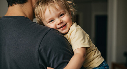 Toddler smiling while being held on parent's shoulder at home  