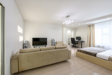 modern apartment interior featuring a sofa, bed, workspace, TV, and minimalist decor in a bright, open layout