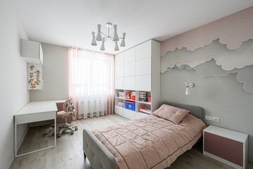 child's bedroom with a bed, desk, storage, and cloud-themed wallpaper. Soft pink accents create a calming atmosphere