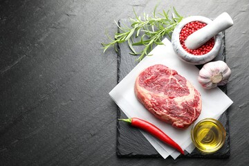 Piece of raw beef meat and spices on black table, flat lay. Space for text