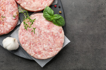 Fresh raw patties for burger and spices on grey table, top view. Space for text